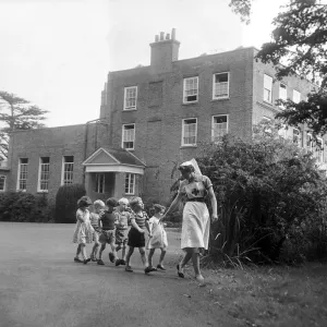 A nurse takes some children for a walk around the grounds of the Beech Hill Convalescent