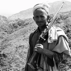 Un vieil homme des tribus pathanes porte un vieux fusil à action par rafale au col de Khyber sur la frontière. Un vieil homme des tribus pathanes porte un vieux fusil à action par rafale au col de Khyber sur la frontière.