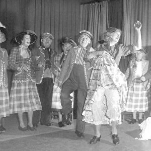 Old people dressed as Pearly Kings and Queens dancing on stage during a concert