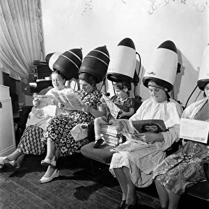 Old women sitting with their heads under a dryer as they get their hair styled