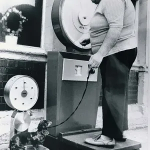 An overweight owner weighs himself on a set of Avery scales An overweight owner weighs himself on a set of Avery scales