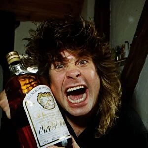 Ozzy Osbourne holding a large bottle of whisky at his home, Friday 27th May 1988