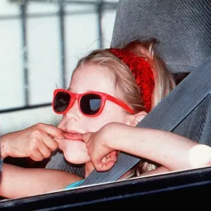 Paula Yates daughter-Peaches in red sunglasses pulling face in back of car on way to