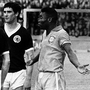 Pele stands next to Scotland player Jim Baxter protesting his innocence with his arms
