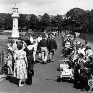 La gente disfrutando del sol de la tarde en el lago Roath Park.