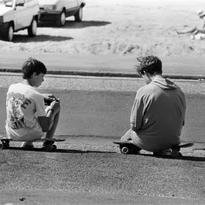 People enjoying a day at Crosby beach. Two boys sitting on skateboards