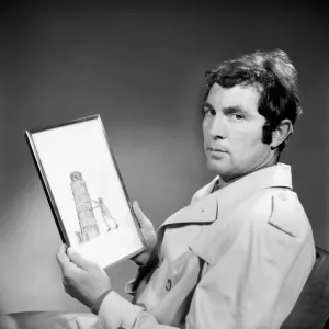 People Men Humour. A man wearing an overcoat holding a framed picture of the leaning