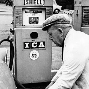 A Petrol pump attendant filling up a cars tank with fuel at a service station