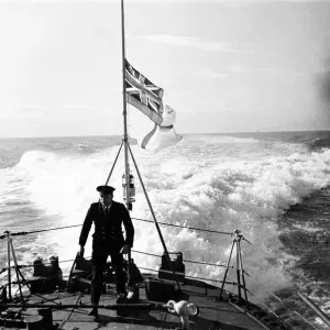 Petty Officer on the quarter deck of a Royal Naval destroyer, White Ensign at half mast Petty Officer on the quarter deck of a Royal Naval destroyer, White Ensign at half mast