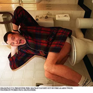 Phil MacKay Grampian TV Presenter with his hands over his ears sitting on toilet wc