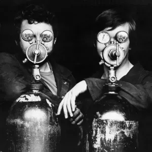 La imagen muestra a 2 (dos) soldadores. Cada uno está parado detrás de un recipiente de gas. La imagen muestra a 2 (dos) soldadores. Cada uno está parado detrás de un recipiente de gas.