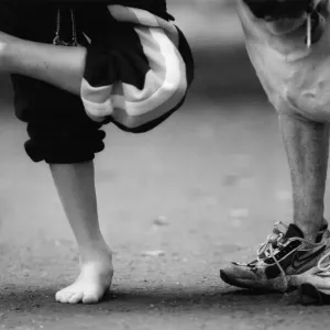 L'image montre un chien portant des chaussures qui appartiennent probablement au jeune garçon à gauche. L'image montre un chien portant des chaussures qui appartiennent probablement au jeune garçon à gauche.