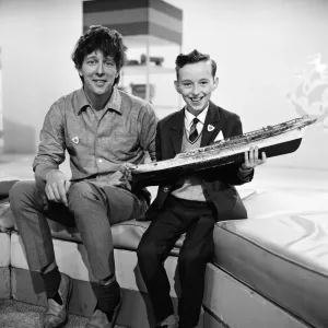 Colour print of a child holding a model boat on the Blue Peter set