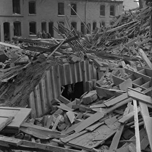 A pile of rubble surrounds an Anderson shelter in the back garden of terrace housing off