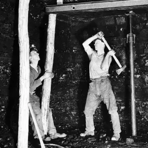 Pitprops being hammered into position under the steel roof supports at Whitehill Colliery
