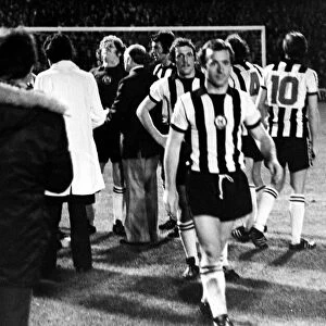 Players and officials gather round Mick Mahoney after Newcastle