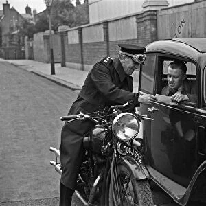 A police motorcyclists issues a warning to a motorist in Hampton, Middlesex