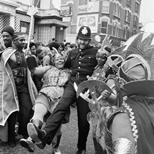 A policeman dances with a woman in costume at Notting Hill carnival