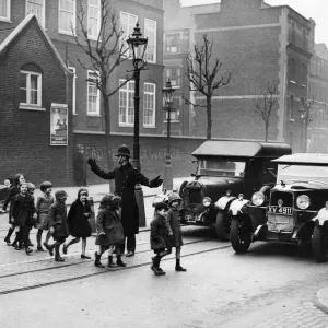 Print of a policeman assisting children to cross the road in London, 1934 Print of a policeman assisting children to cross the road in London, 1934