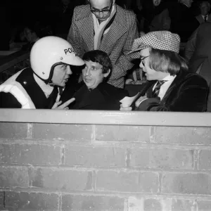 Un policía hablando con Graham Taylor y Elton John, quienes están viendo el partido de fútbol.