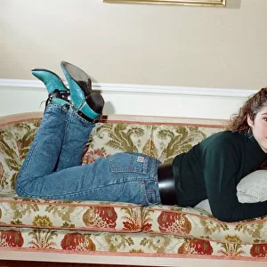 Pop singer Gloria Estefan poses lying down on a sofa in her hotel room on a visit to