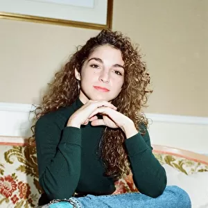 Pop singer Gloria Estefan poses sitting down on a sofa in her hotel room on a visit to