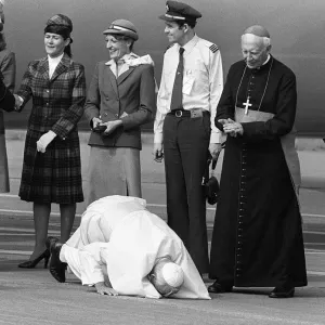 Der Papst Johannes Paul II kniet sich hin und küsst den Boden auf dem Flughafen von Kardiff bei seiner Besuch Der Papst Johannes Paul II kniet sich hin und küsst den Boden auf dem Flughafen von Kardiff bei seiner Besuch