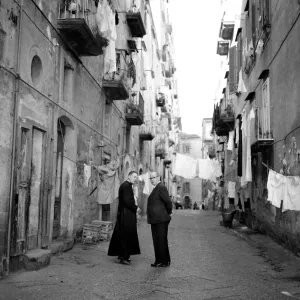 A priest chats to a elderly man in a street in the old town quarter of Naples in Southern