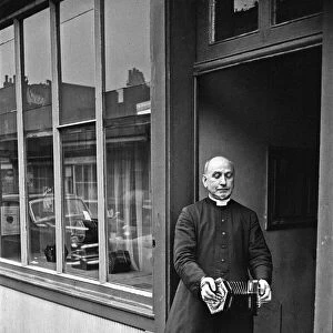 A priest plays a concertina outside Crabbs Concertina Shop in Liverpool Street