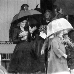 Princess Diana and The Queen Mother hide underneath their umbreallas during a heavy