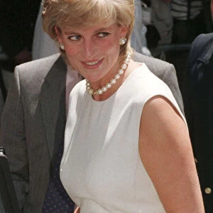 Princess Diana, wearing a white dress and necklace during a visit to a rehabilitation