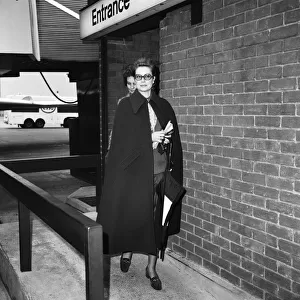 Princess Grace of Monaco, wearing a full length cape, as she arrives at Heathrow Airport