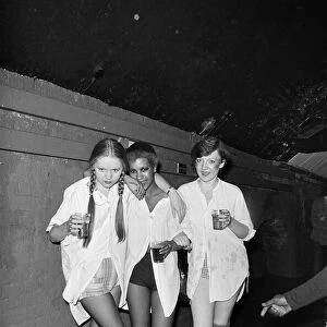 Punk rocker girls at disco holding beer glasses 1976