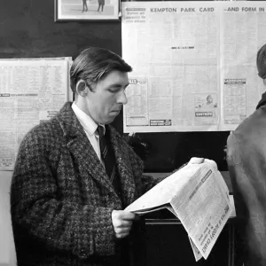 A punter checks the racing guide in a newspaper before making his bet at a race