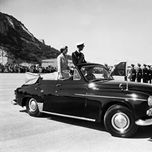 Queen Elizabeth II and the Duke of Edinburgh in an open car reviewing troops on a visit