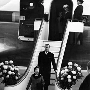 Queen Elizabeth II and Prince Philip walk down the gangway from the plan on their return