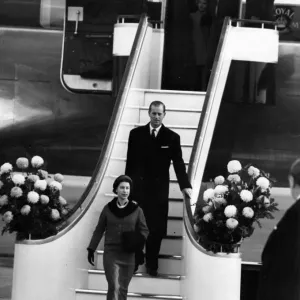 Queen Elizabeth II and Prince Philip walk down the gangway from the plan on their return