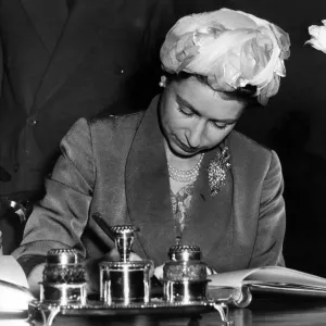 Queen Elizabeth II signs the visitors book at Stratford Town Hall during her visit