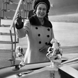 Queen Elizabeth II waves to onlookers, as she walks to her car from the aircraft