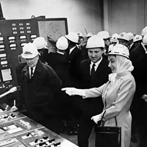 Queen Elizabeth II wearing protective clothing, watches the control panel of the new
