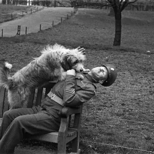 One of the Queens Guardsmen in a park with a dog, London, circa February 1948