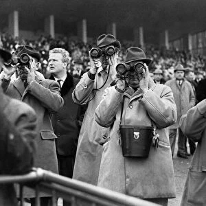 Racing at Sandown Park. Racegoes watching the action using binoculars January 1968