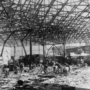 RAF ground crew clear up wreckage inside a bomb shattered hangar at an airport near RAF ground crew clear up wreckage inside a bomb shattered hangar at an airport near