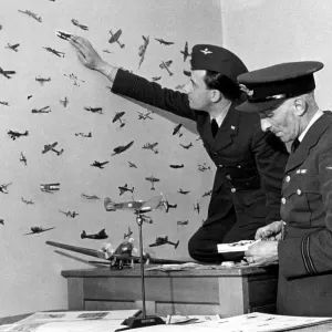 An RAF officer preparing cut outs of enemy planes from magazines to stick on the walls of An RAF officer preparing cut outs of enemy planes from magazines to stick on the walls of