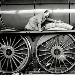 Railway worker cleans the sign on the wheels on the Flying Scotsman steam train