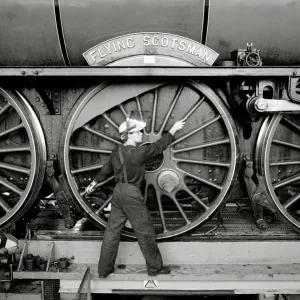 Railway worker stands beside the Flying Scotsman steam train wheels print Railway worker stands beside the Flying Scotsman steam train wheels print