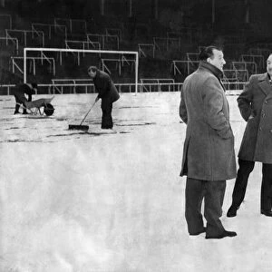 Referee Roy Capey weighs up the snow covered Anfield pitch with Liverpool manager Bob