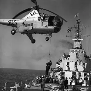 Richard Dimbleby descends from a Westland Dragonfly helicopter on to the deck of HMS