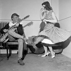 Rock and Roll singer Tommy Steele plays his guitar as girl dances for him June 1957