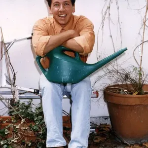 Ross King TV presenter in his garden holding a watering can
